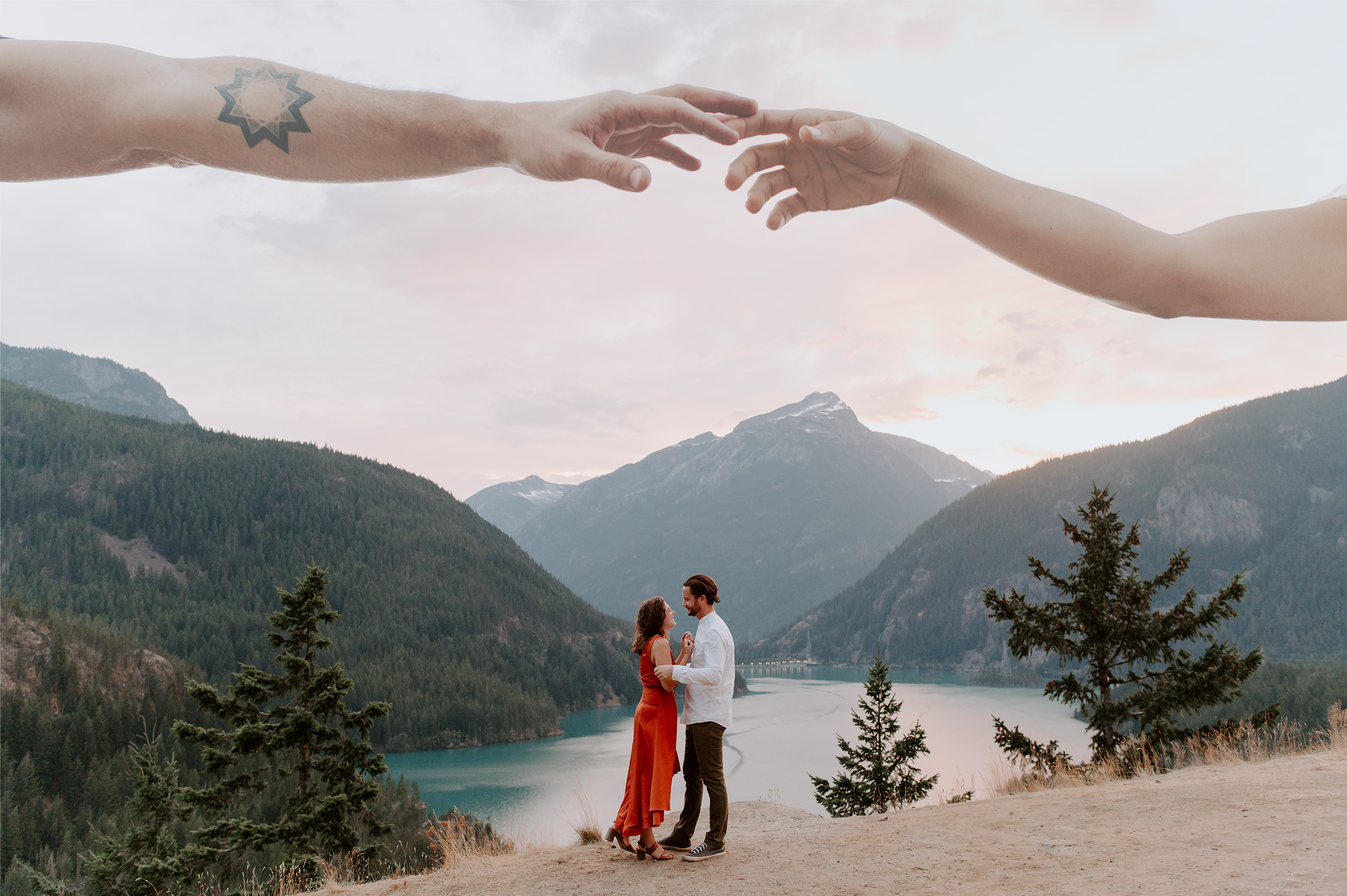 a couple embraces at the diablo lake overlook with mountains lit by sunset in the background