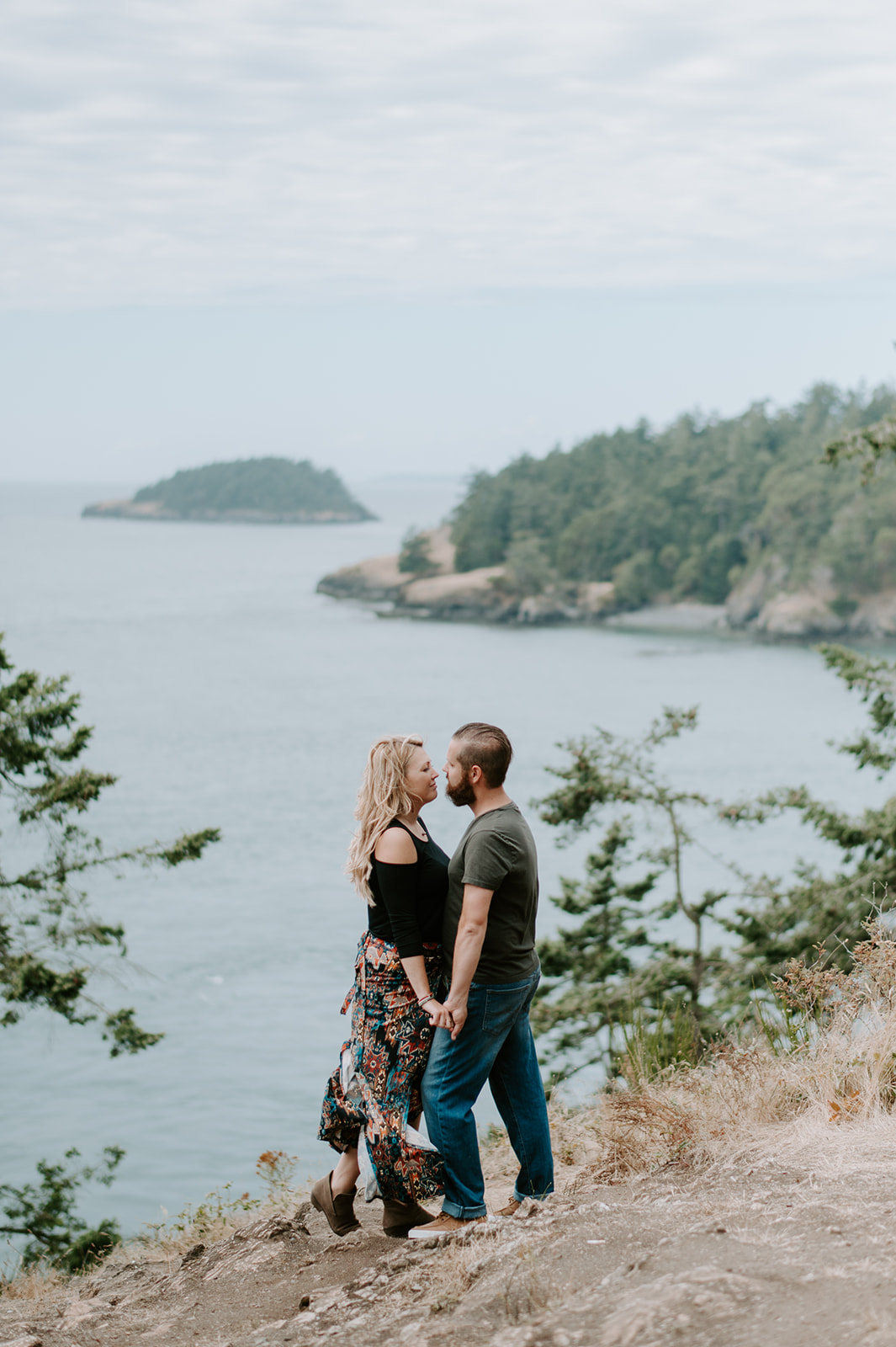 Couple holding hands and looking into each other's eyes with scenic water views during their Deception Pass anniversary session.