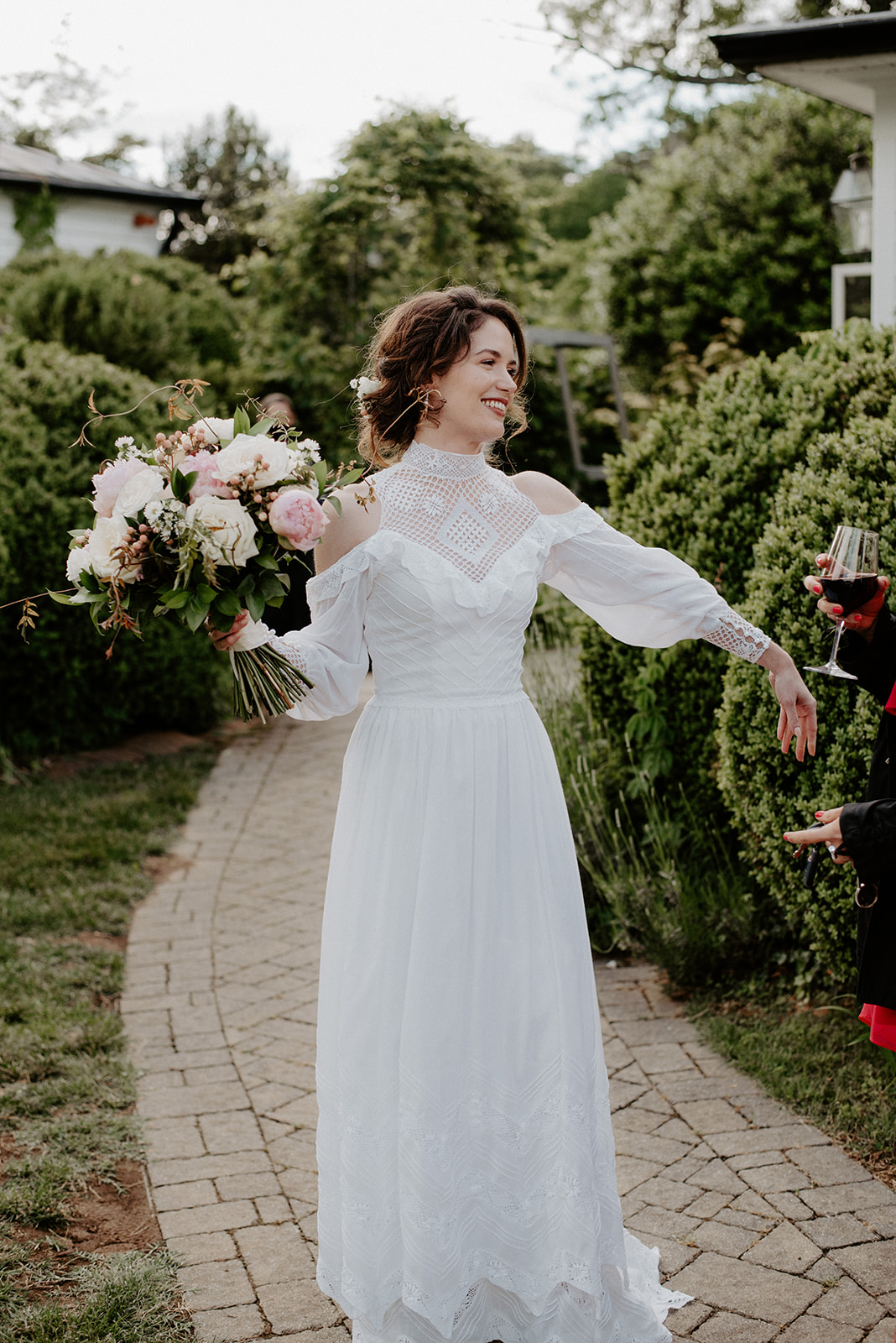 Bride holding a lush bouquet walking through a garden on her wedding day