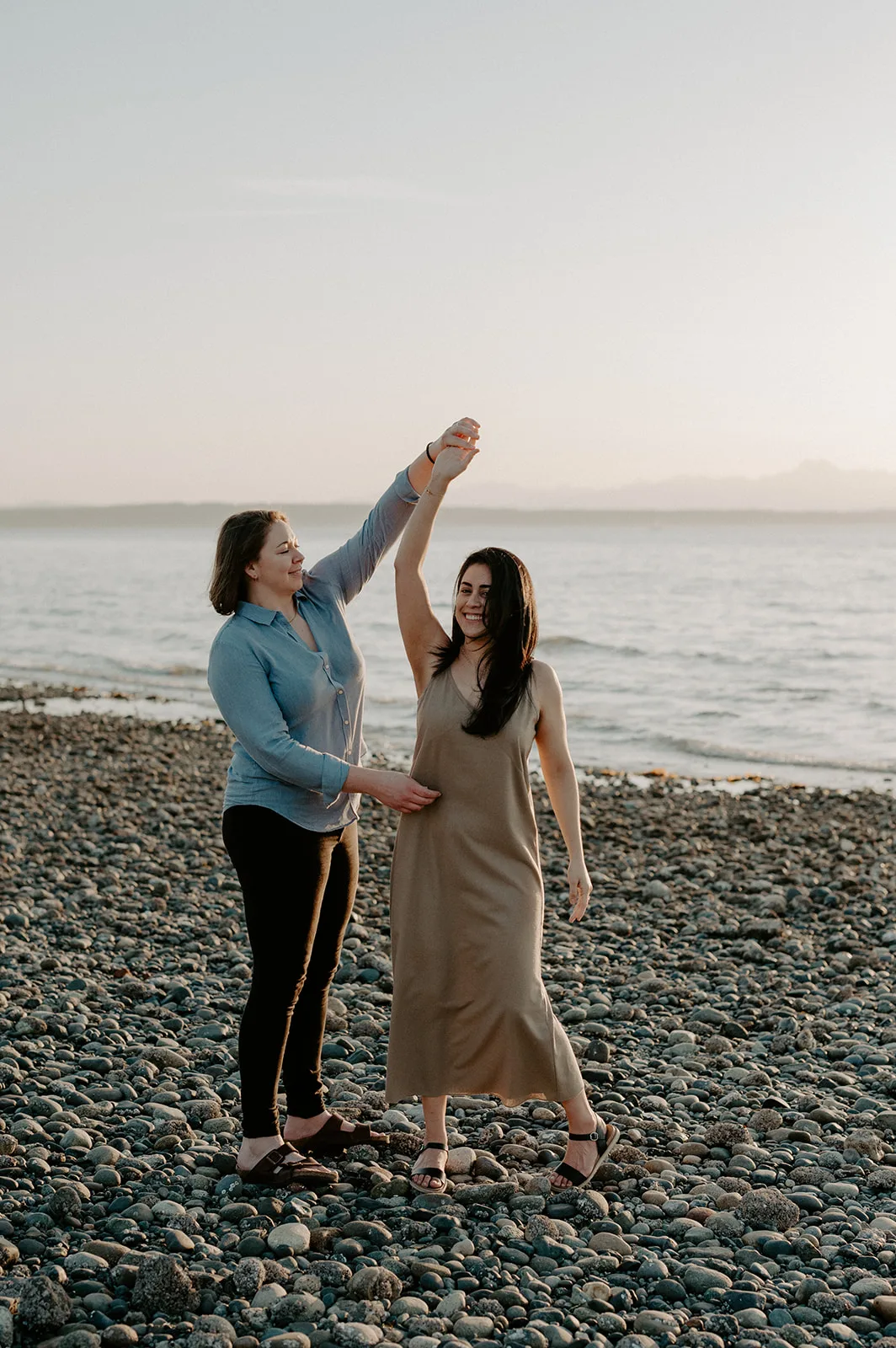 a couple dancing during their sunset engagement session at carkeek park