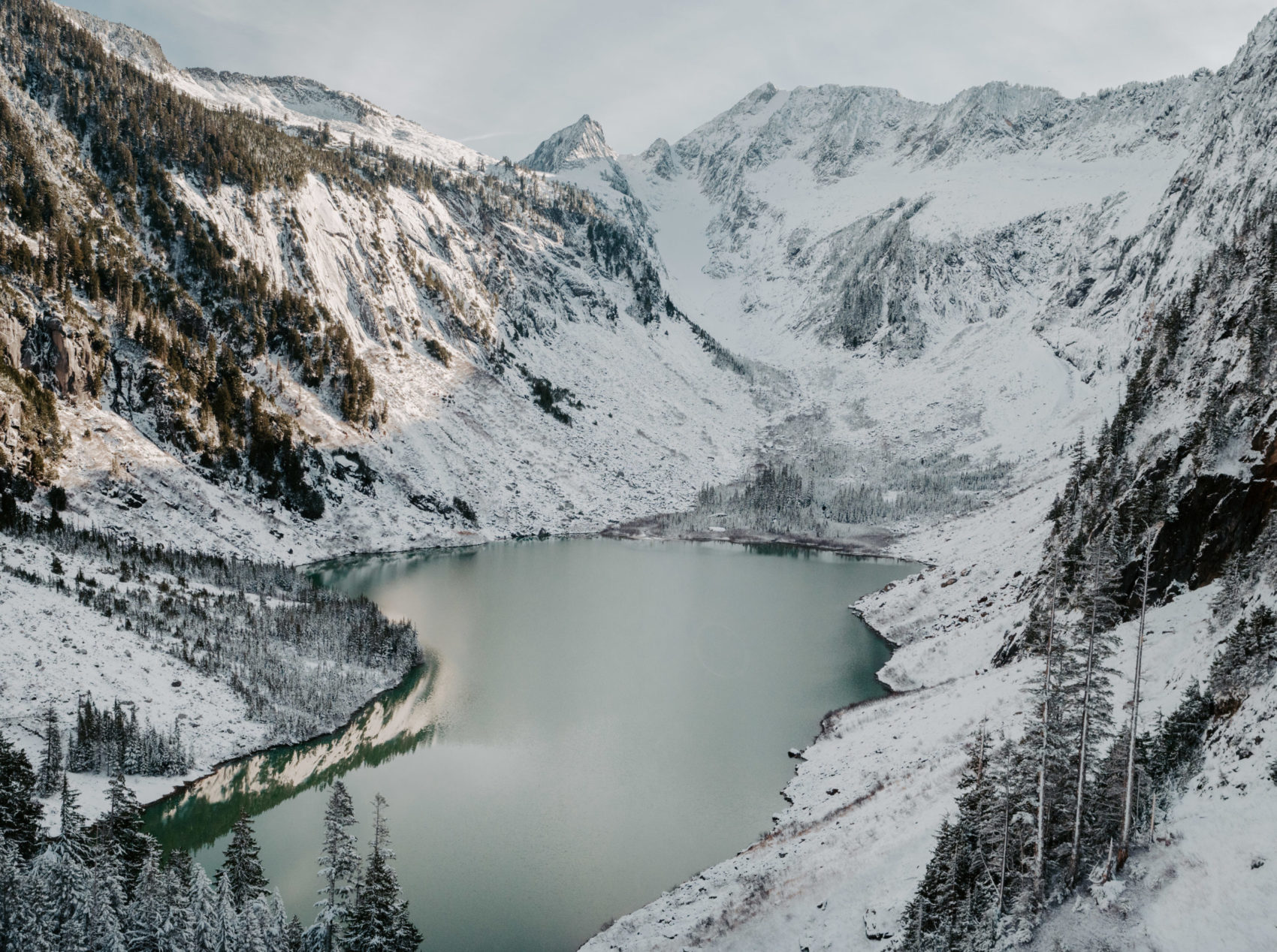 A serene alpine lake surrounded by snow-covered mountains in the Cascade Range of Washington.