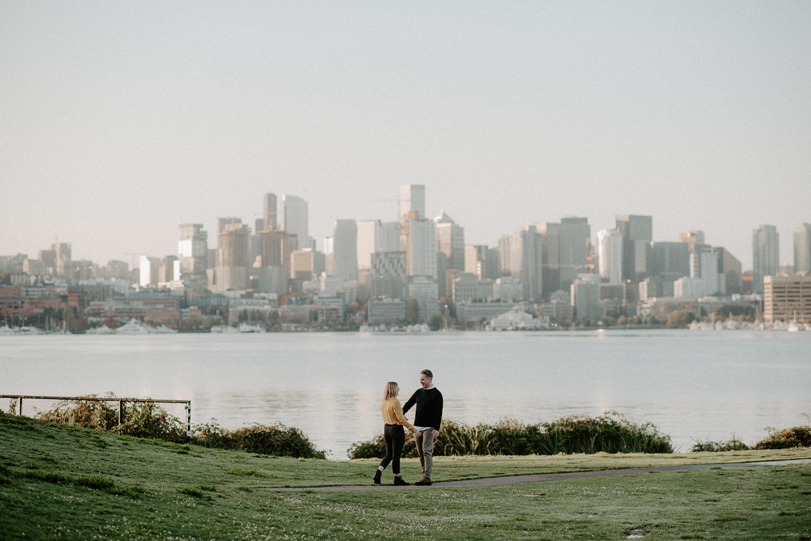 Couple walking along the waterfront at Gas Works Park with the Seattle skyline in the background