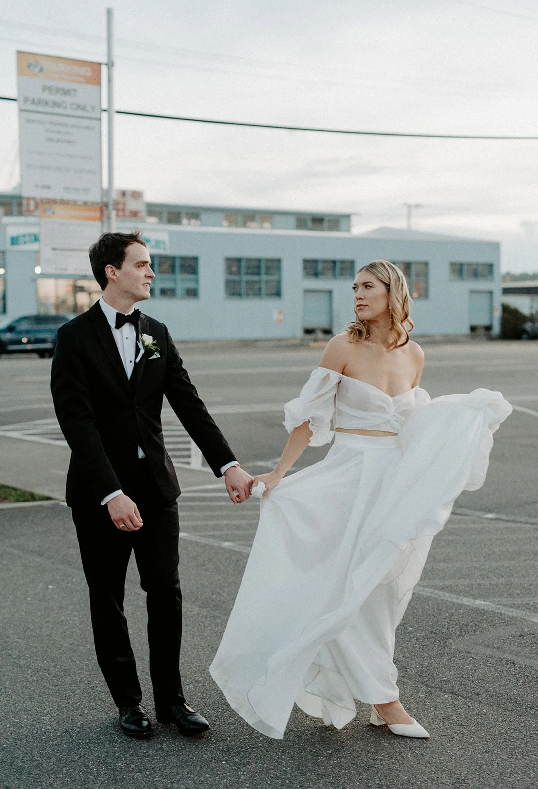 Bride and groom holding hands while crossing a city street on their wedding day