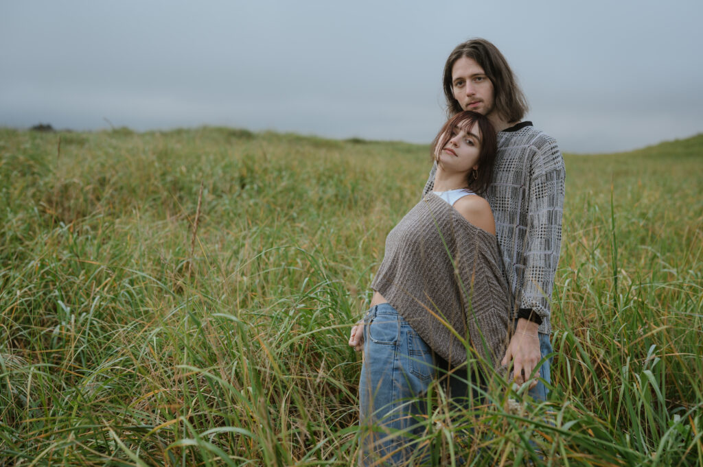 newly engagement couple in a meadow posing tp camera
