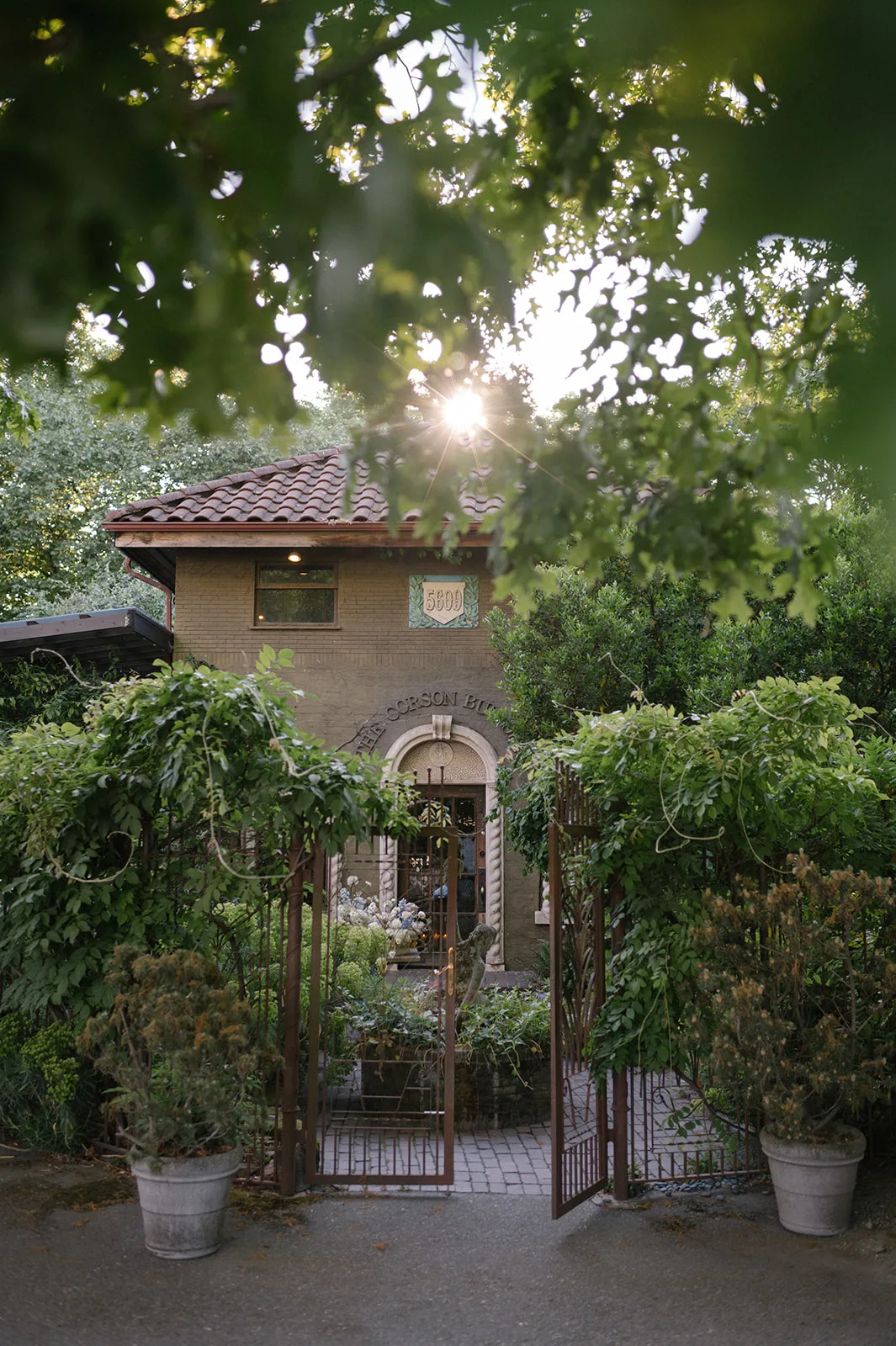 The sun peeks through the lush greenery surrounding The Corson Building, showcasing its historical brick facade and romantic courtyard, ideal for intimate Seattle weddings.