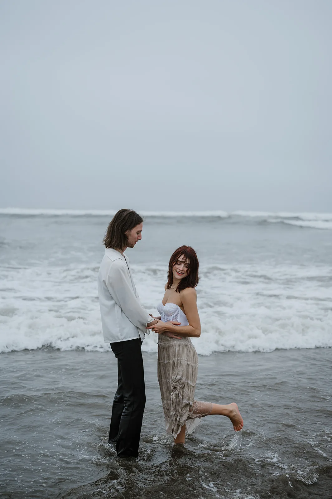 Seashore Sentiments - Engagement Romance on the Oregon Beach Couple standing in the surf, sharing a loving gaze on the Oregon coast