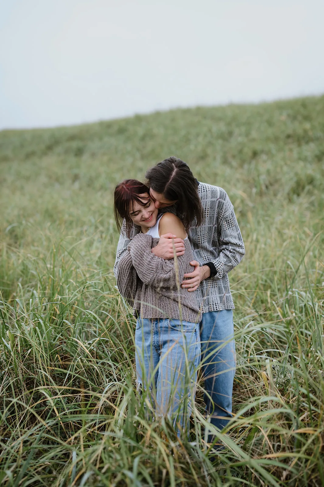 Joy in the Coastal Meadow - Engaged Couple on the Oregon Coast Couple sharing a close and joyous embrace in the lush fields of the Oregon coast