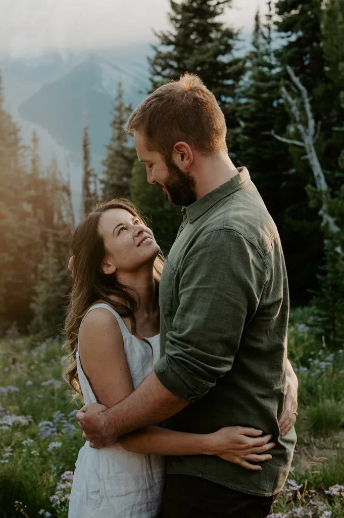 romantic engagement couple closely making eye contact at a green hill area