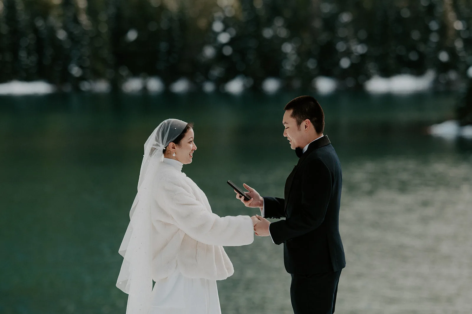Bride and groom holding hands and exchanging vows in a snowy elopement ceremony.
