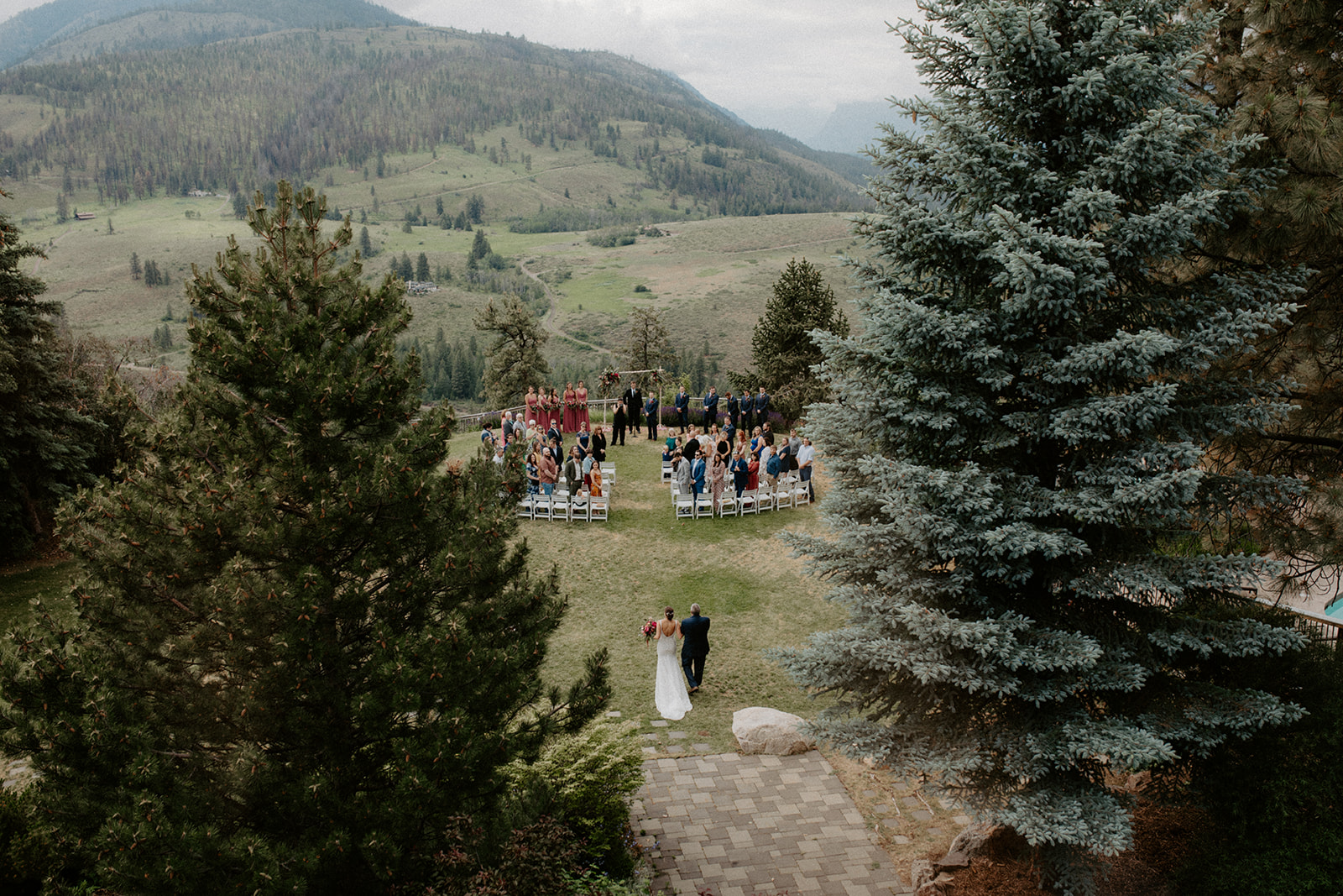 Outdoor mountain wedding ceremony with guests gathered overlooking a scenic valley