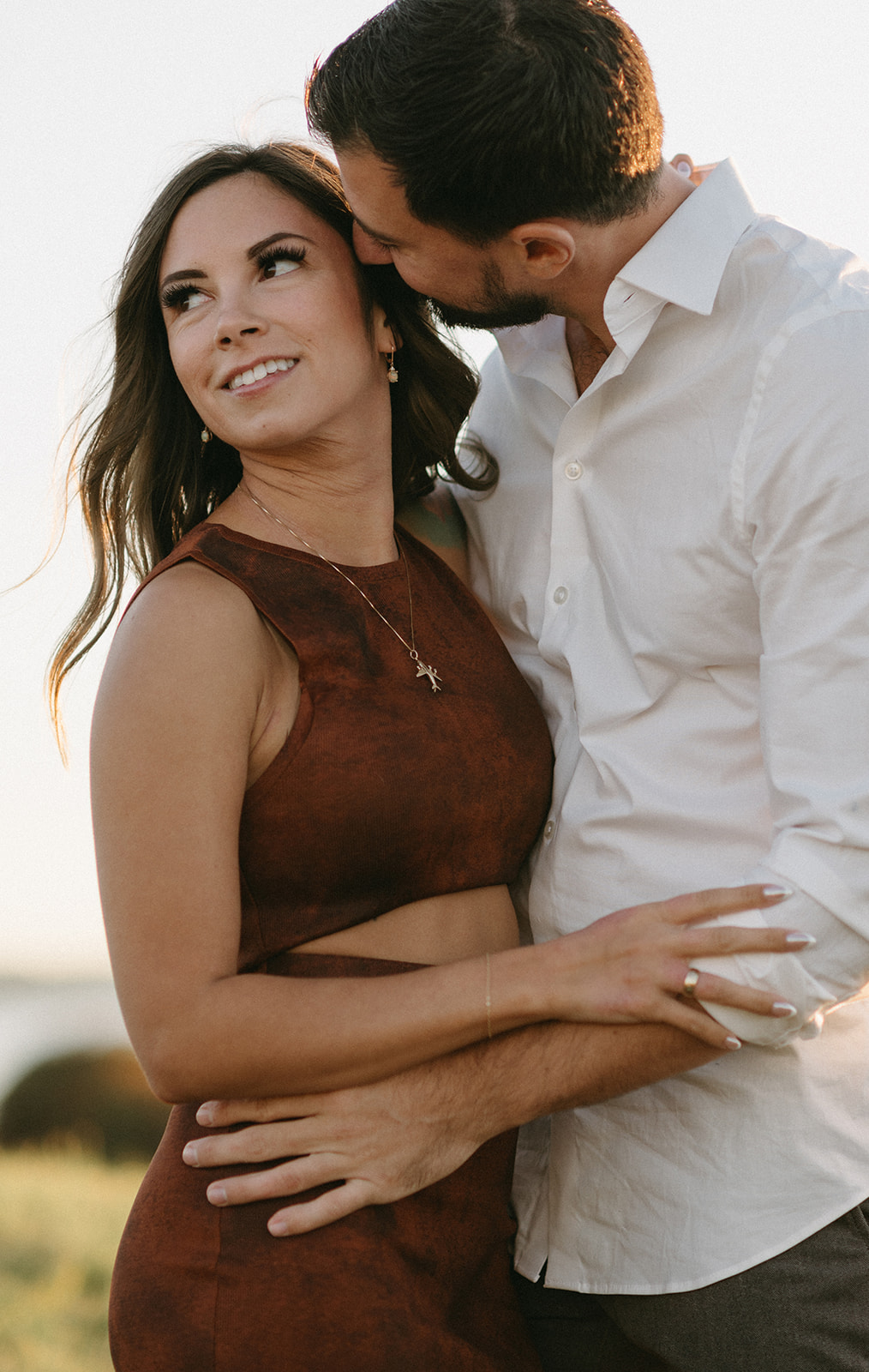 A man kissing a woman's forehead while she smiles at Chambers Bay.