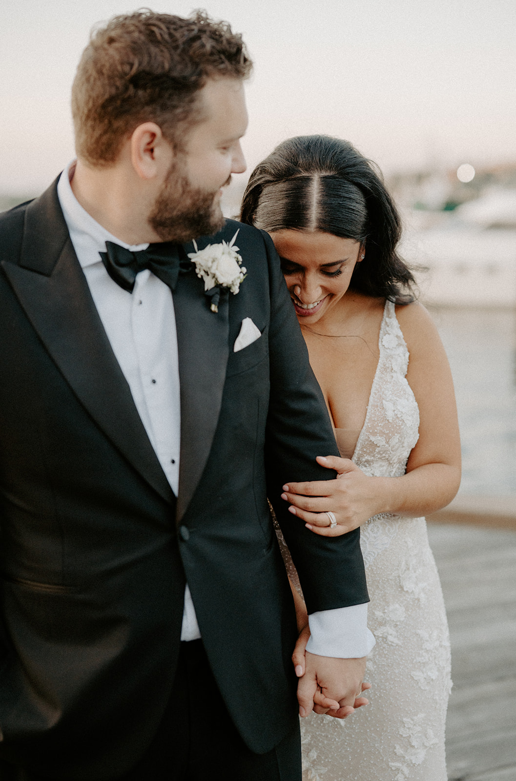 Bride and groom walking hand in hand along the waterfront on their wedding day