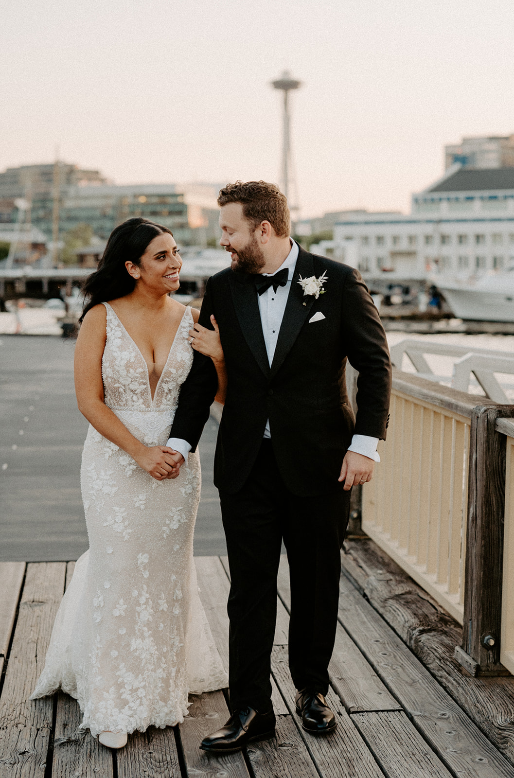 Bride and groom walking together on a dock, smiling at each other during their Dockside at Duke’s wedding.