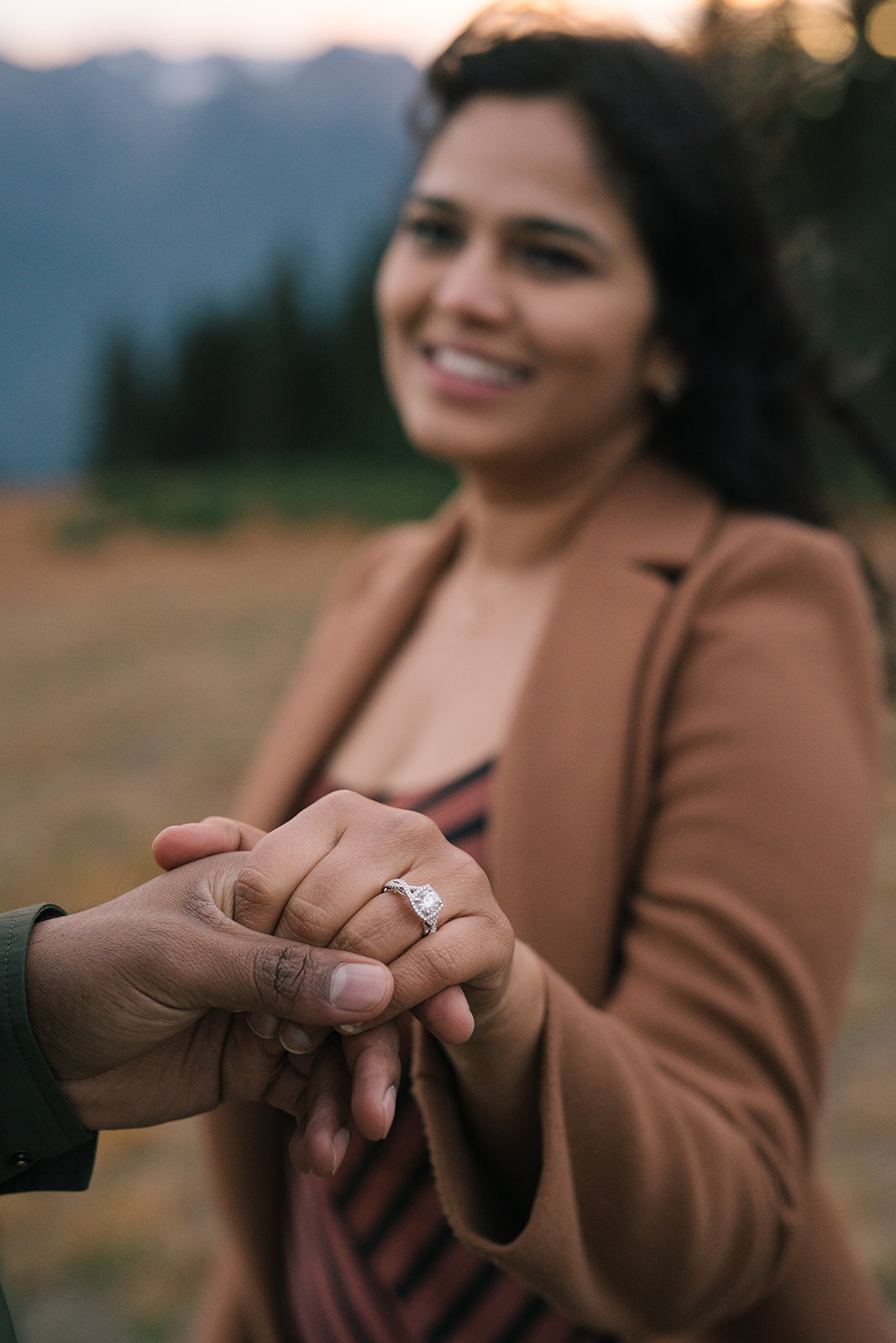 Close-up of an engagement ring as one partner holds the other's hand.