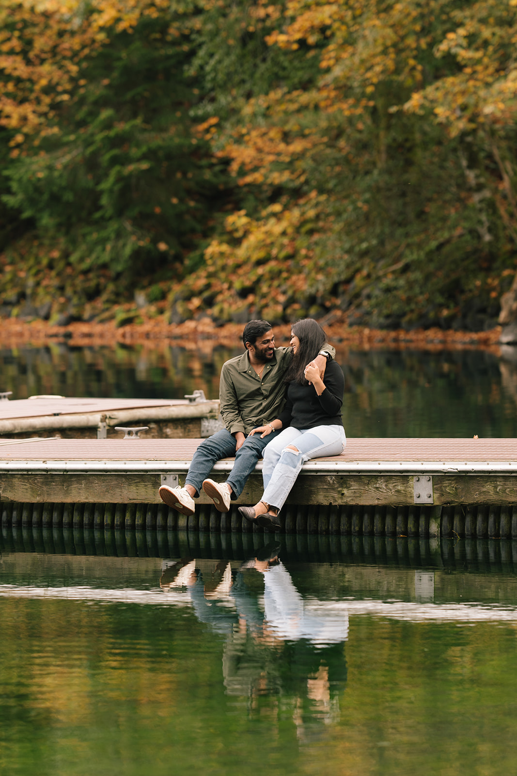 Madhu and Sudesh holding hands on the dock with the Olympic mountains in the background.