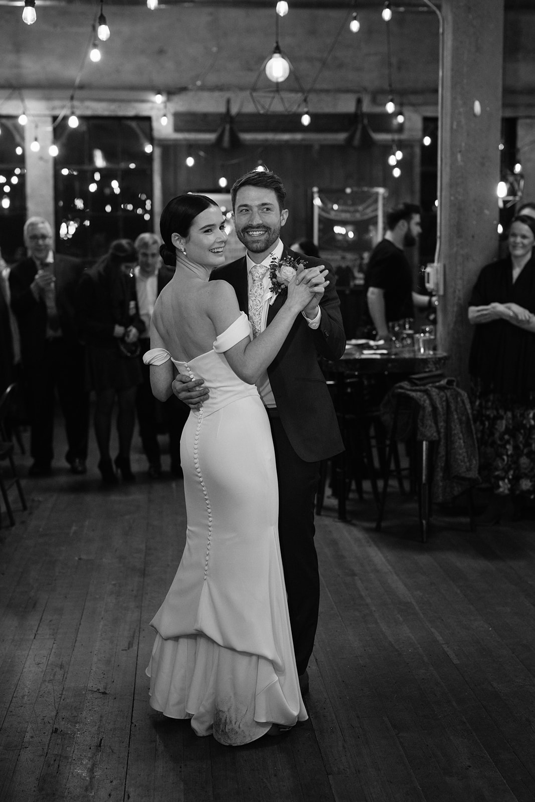 Bride and groom share their first dance surrounded by family and friends.