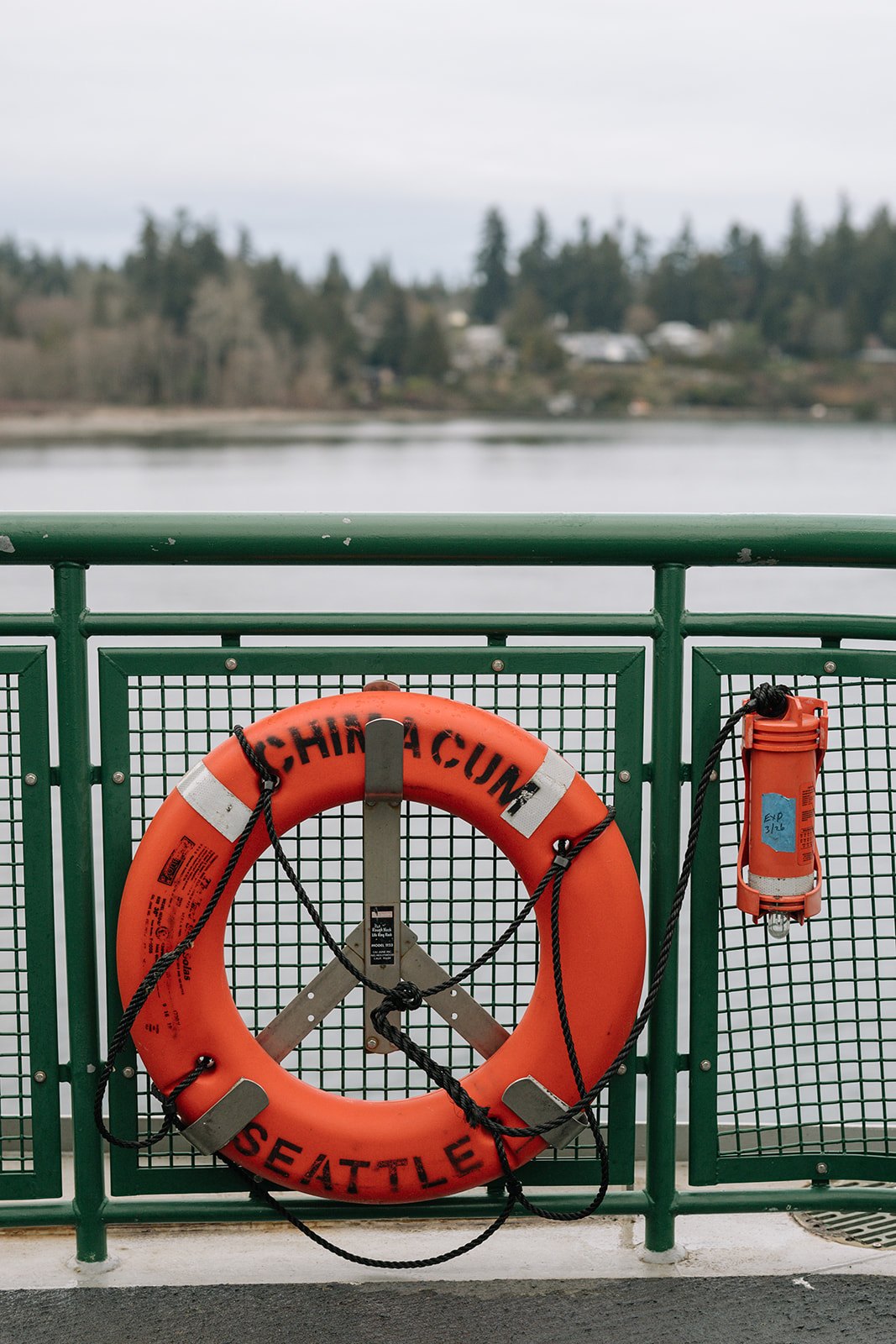 A lifebuoy labeled "Chimacum Seattle" secured to a Washington State ferry railing.