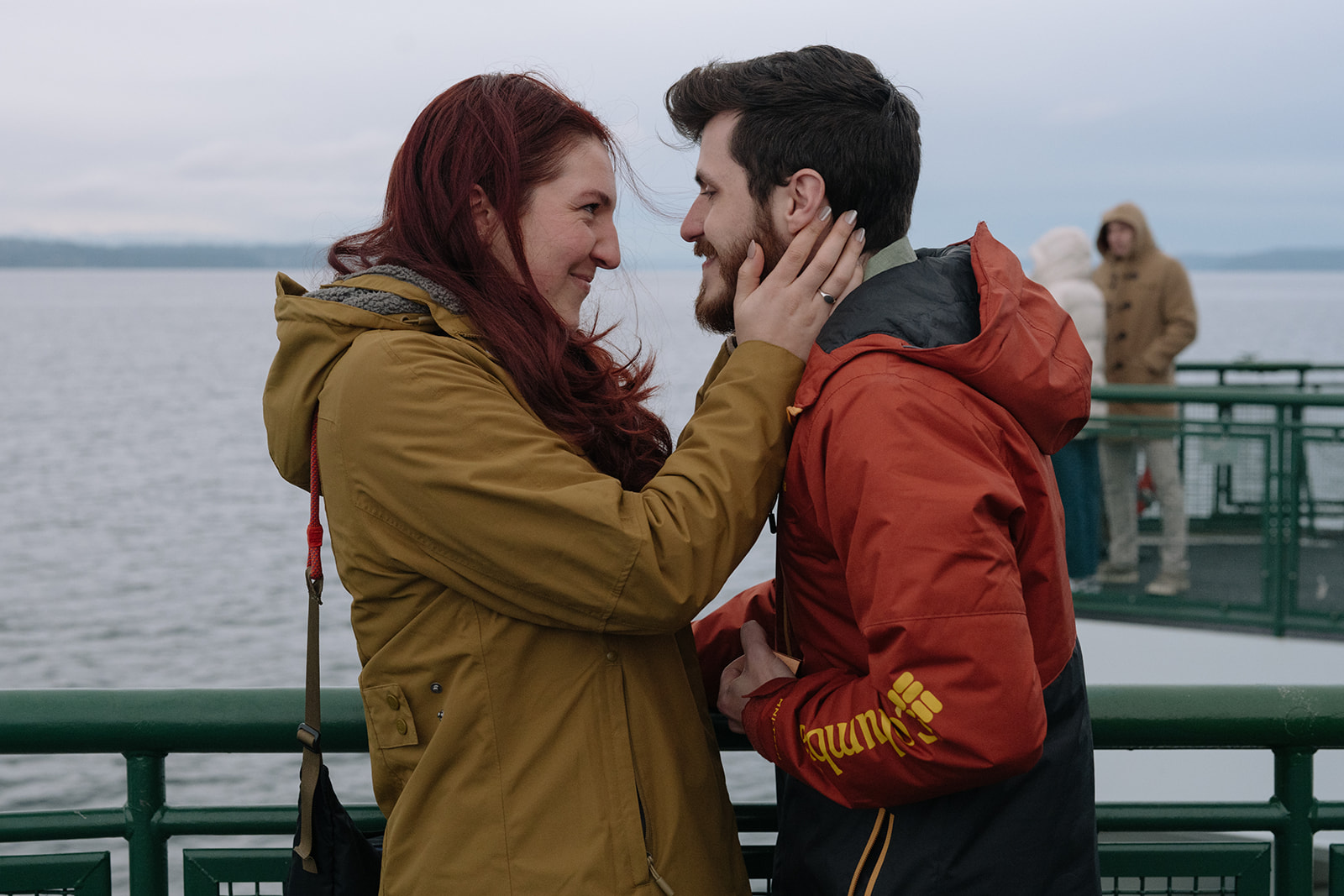 A newly engaged couple looks at each other with love, standing on the ferry deck.