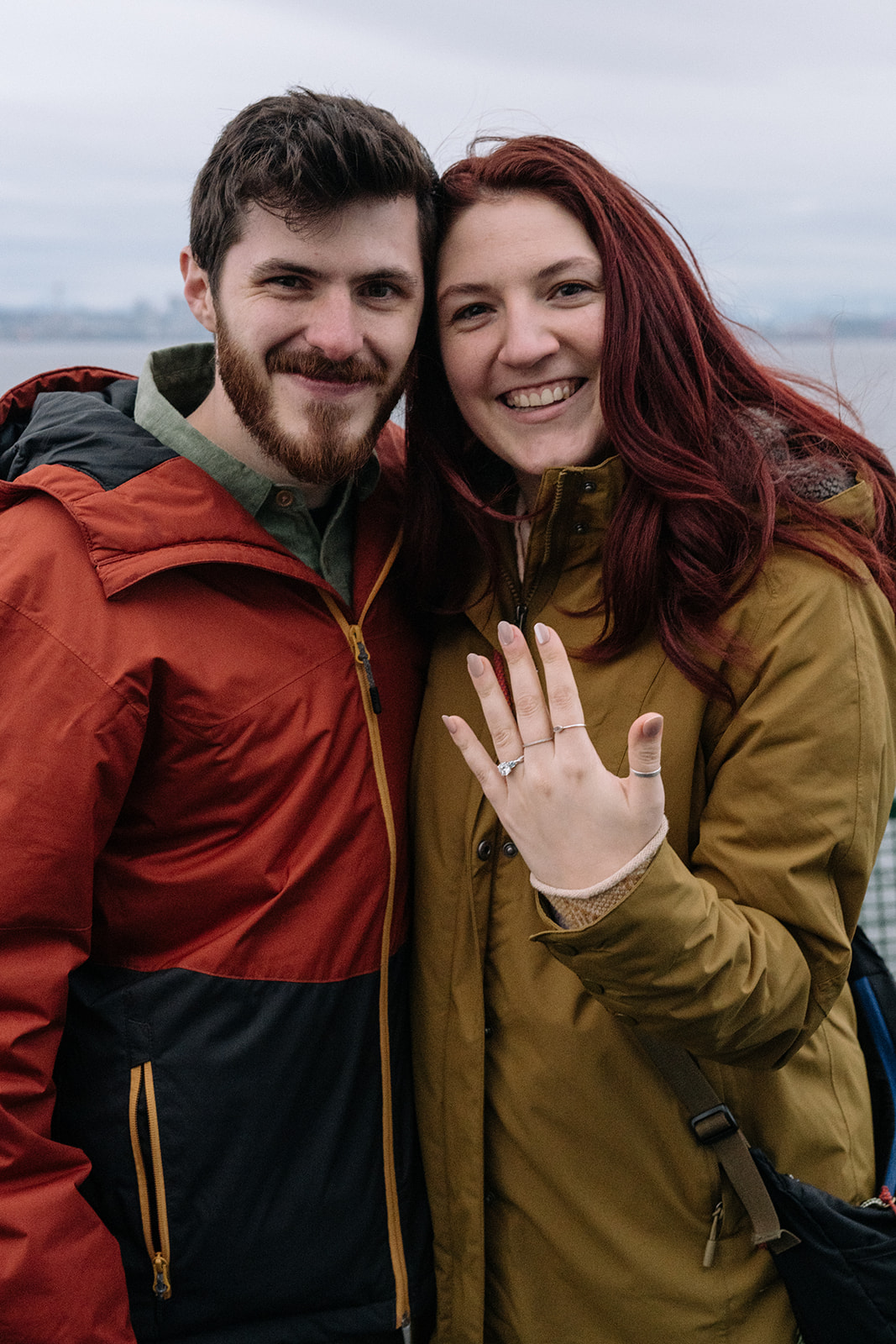 A couple smiles at the camera, the engagement ring on full display after a Washington ferry proposal.