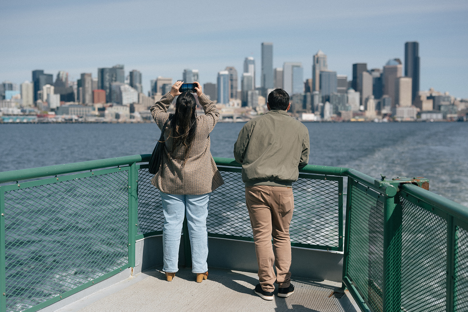 Alyssa holds her phone up to take a photo of the Seattle skyline from the ferry