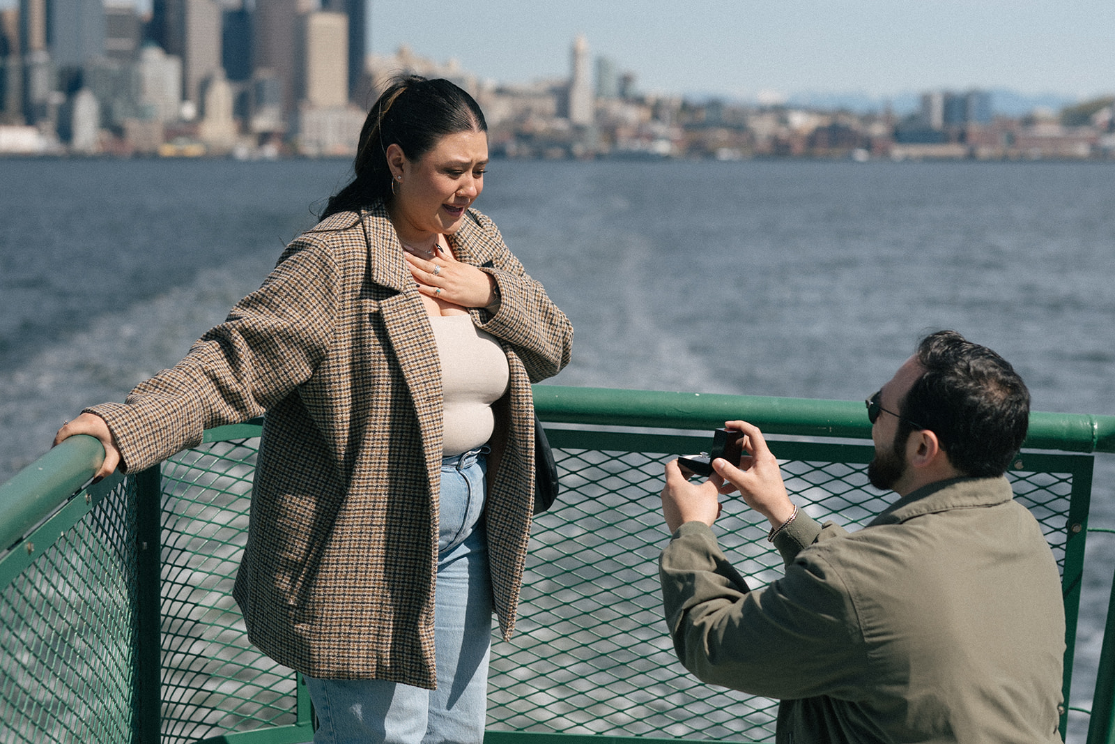 Alyssa holds her hand to her chest as Johnny proposes on the ferry