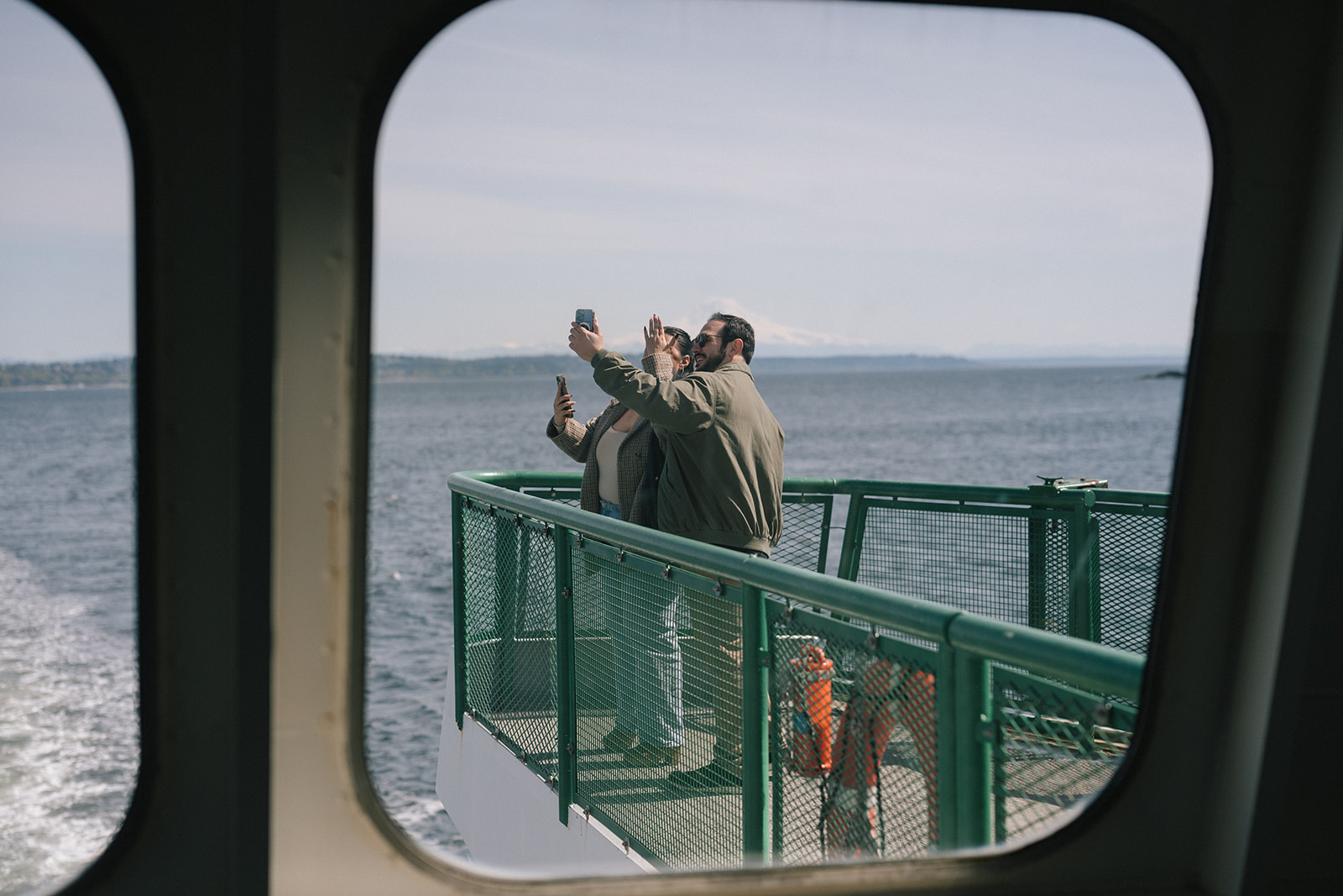 View through a ferry window of Johnny and Alyssa celebrating on deck