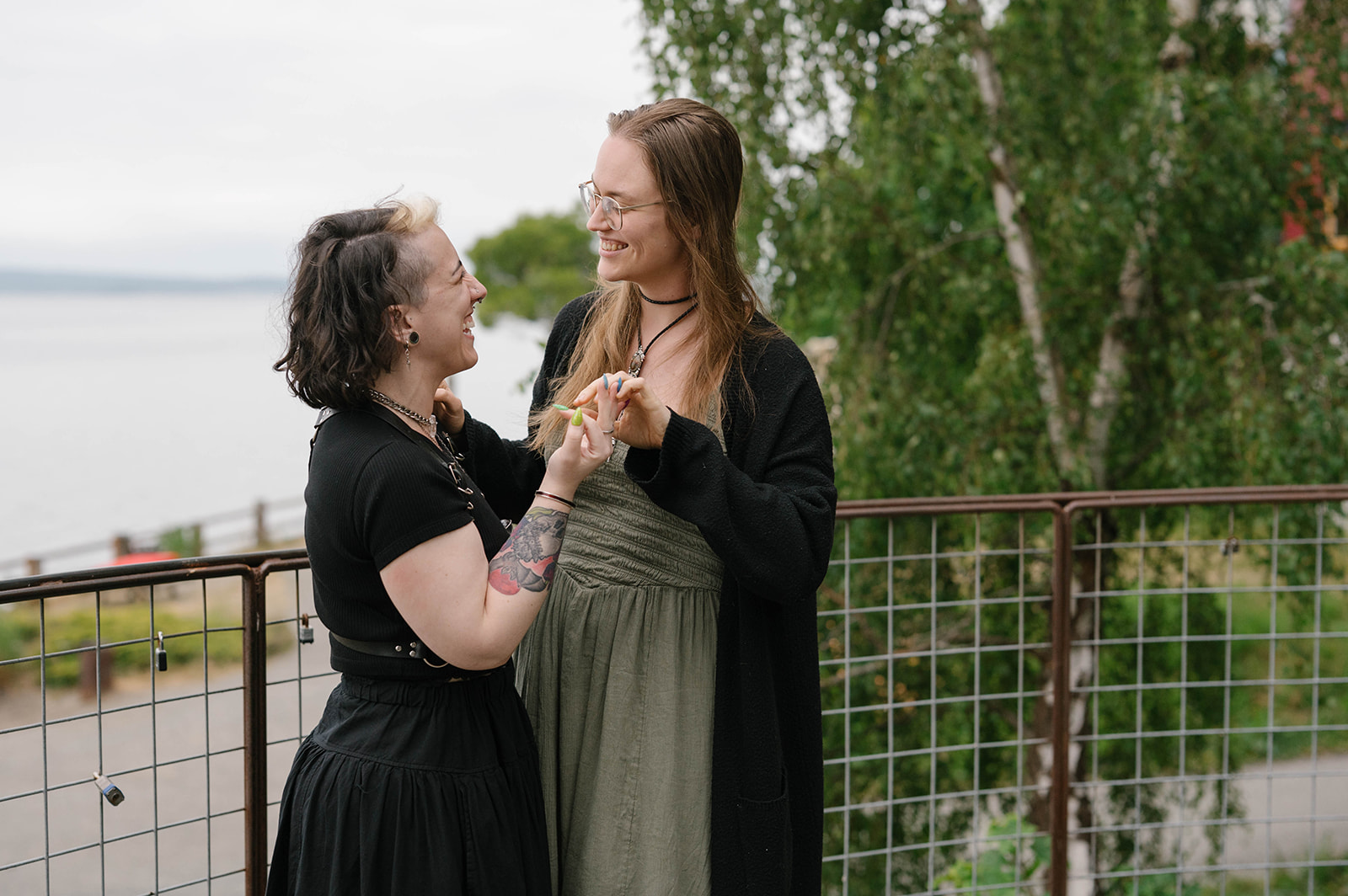 A newly engaged couple holding hands and admiring an emerald engagement ring at a Whidbey Island viewpoint.