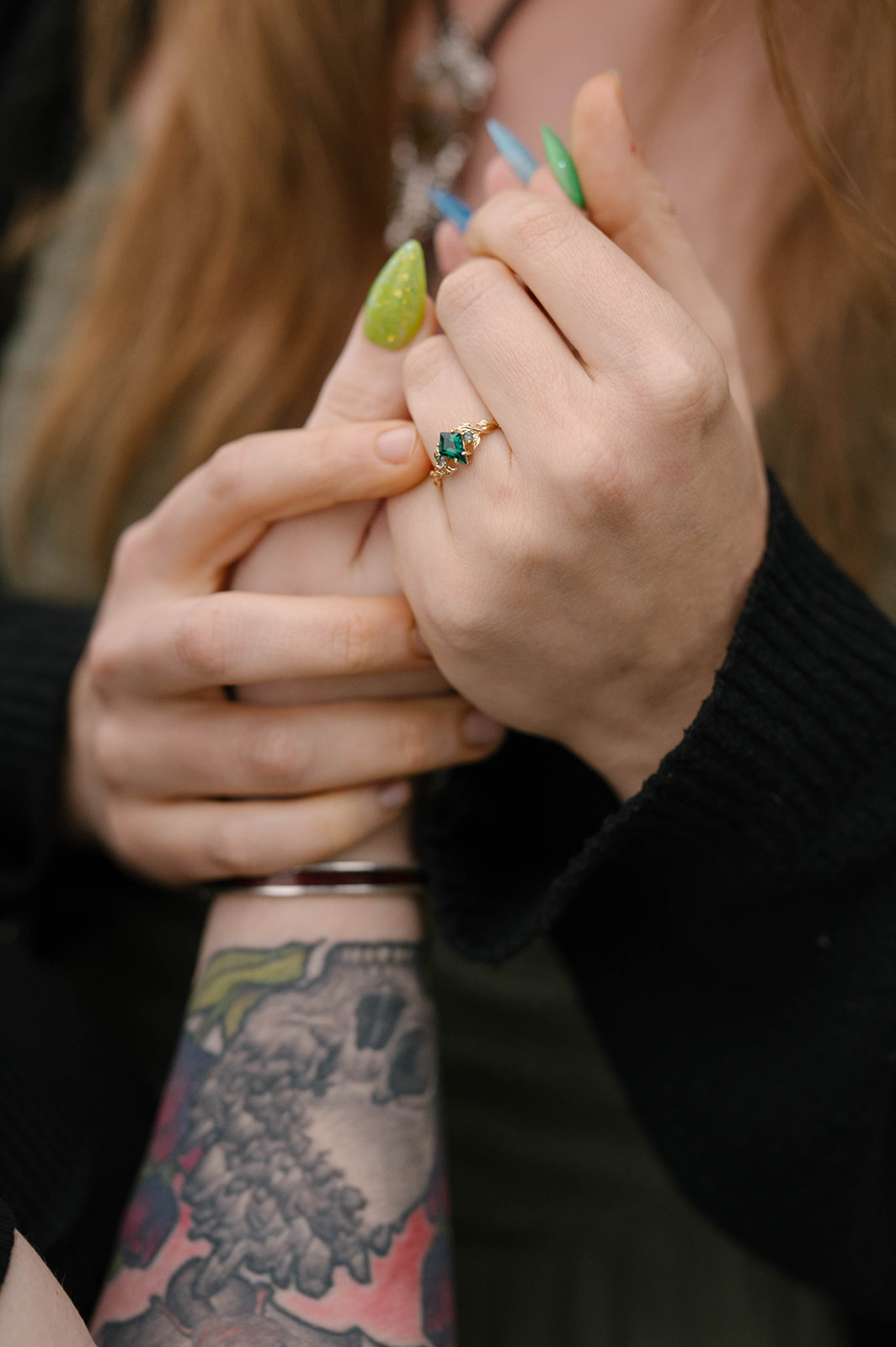 Close-up of an emerald engagement ring and rainbow-colored nails after a Whidbey Island proposal.