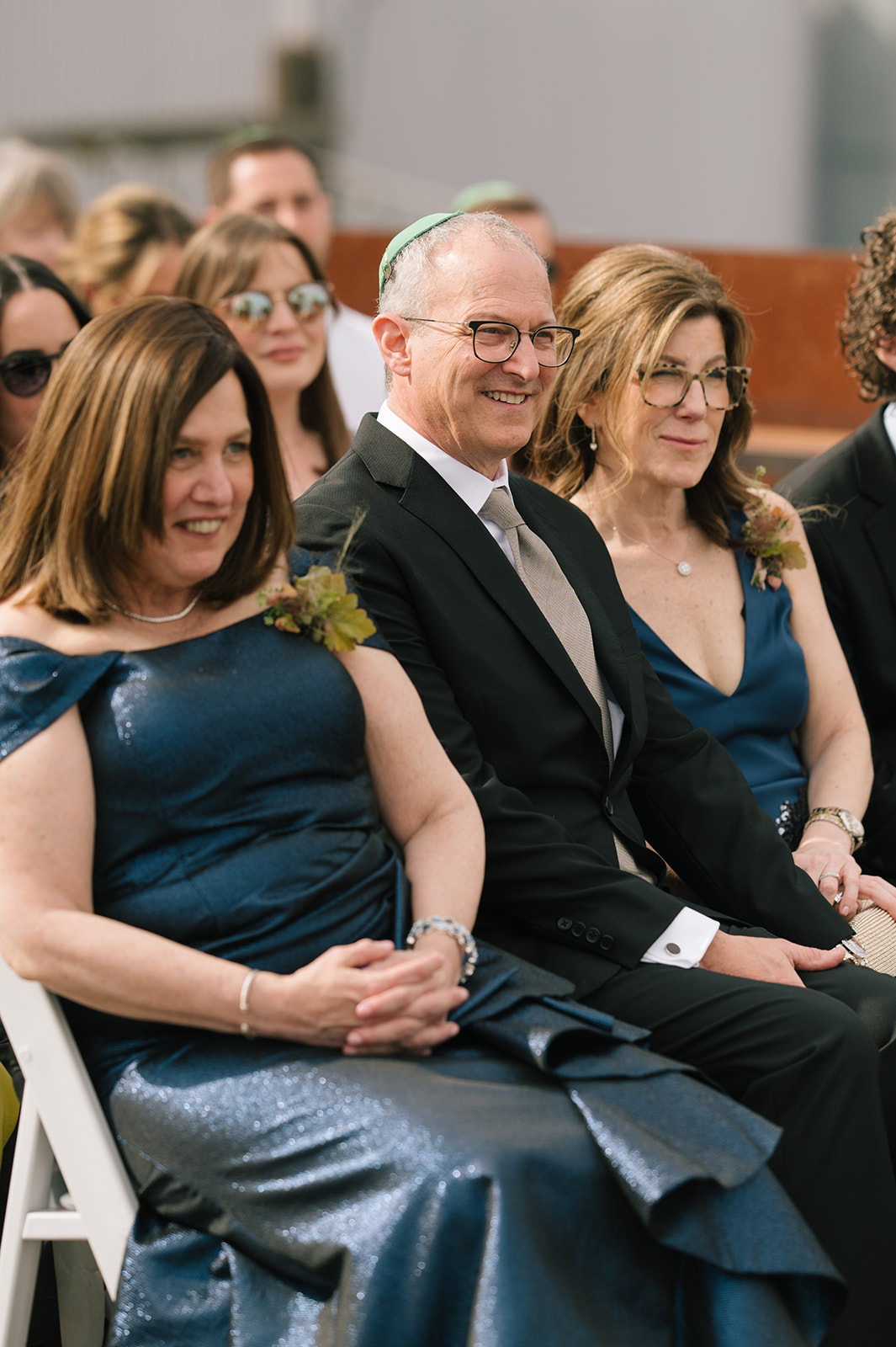 Parents of the bride seated and smiling during the Fremont Foundry rooftop wedding ceremony