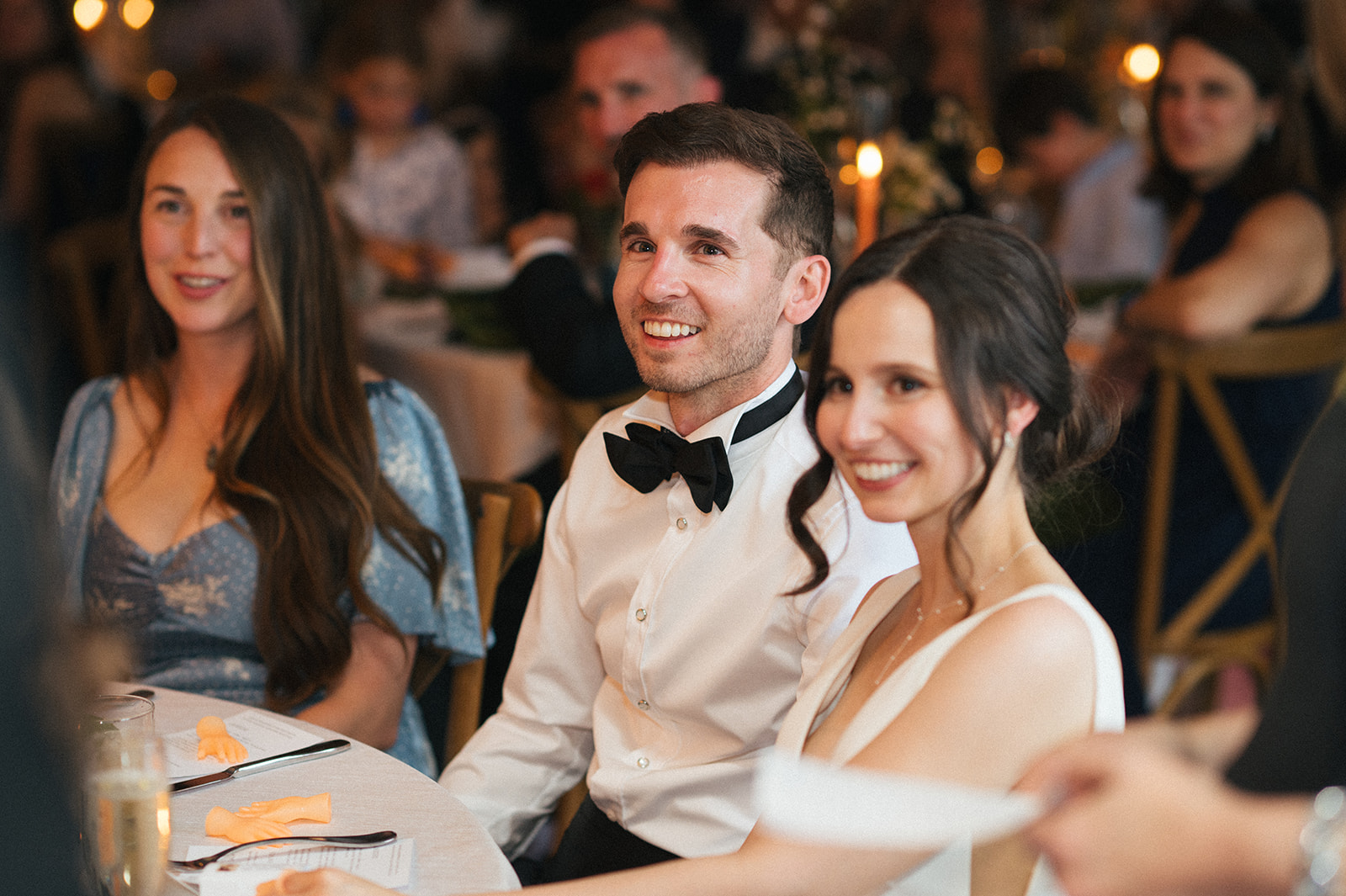 Bride and groom smiling at the camera while seated at their reception at the Fremont Foundry in Seattle