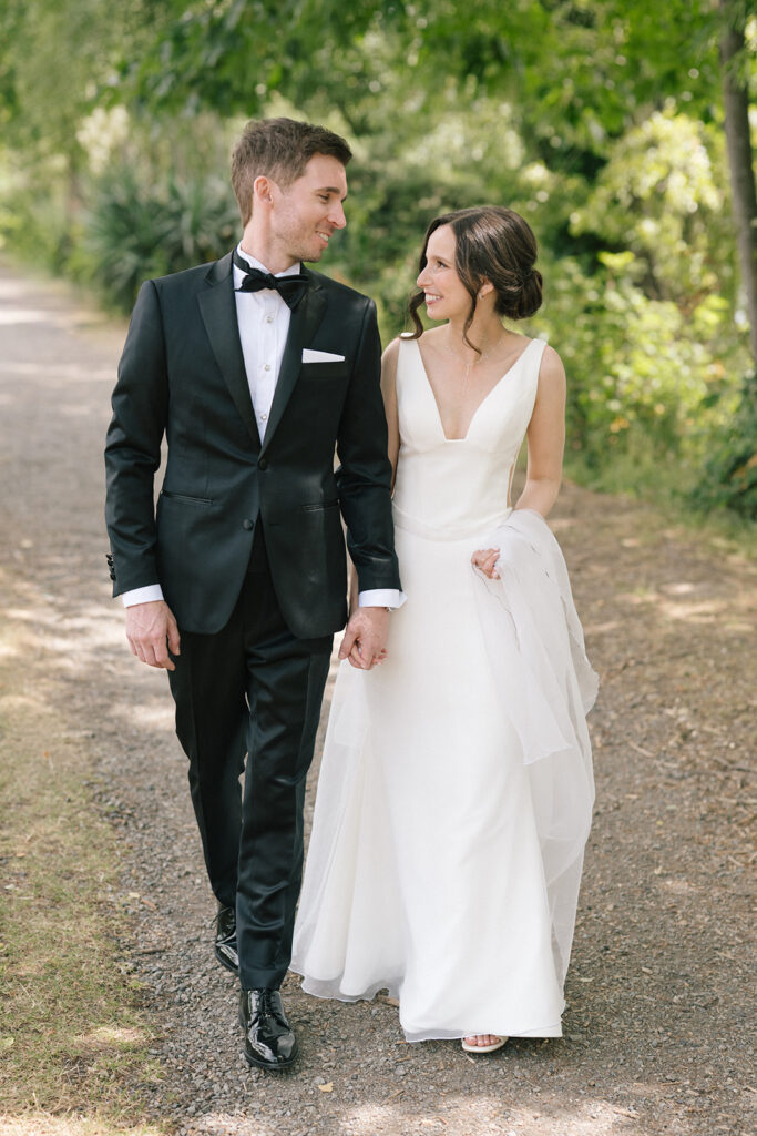 Bride and groom walking hand in hand along a shaded path during Fremont Foundry wedding portraits