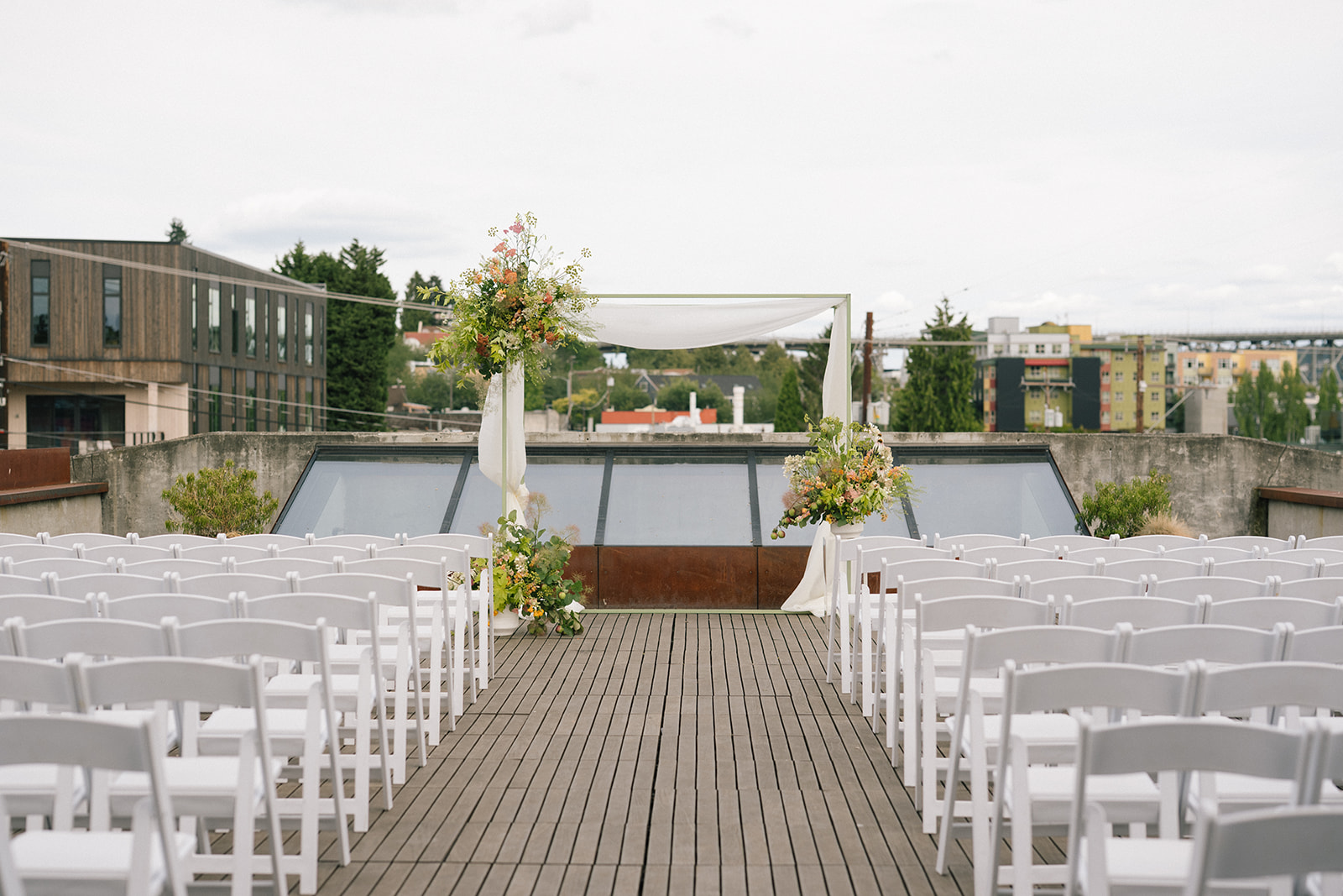 Rooftop wedding ceremony setup at the Fremont Foundry in Seattle with white chairs, floral arch, and city skyline views