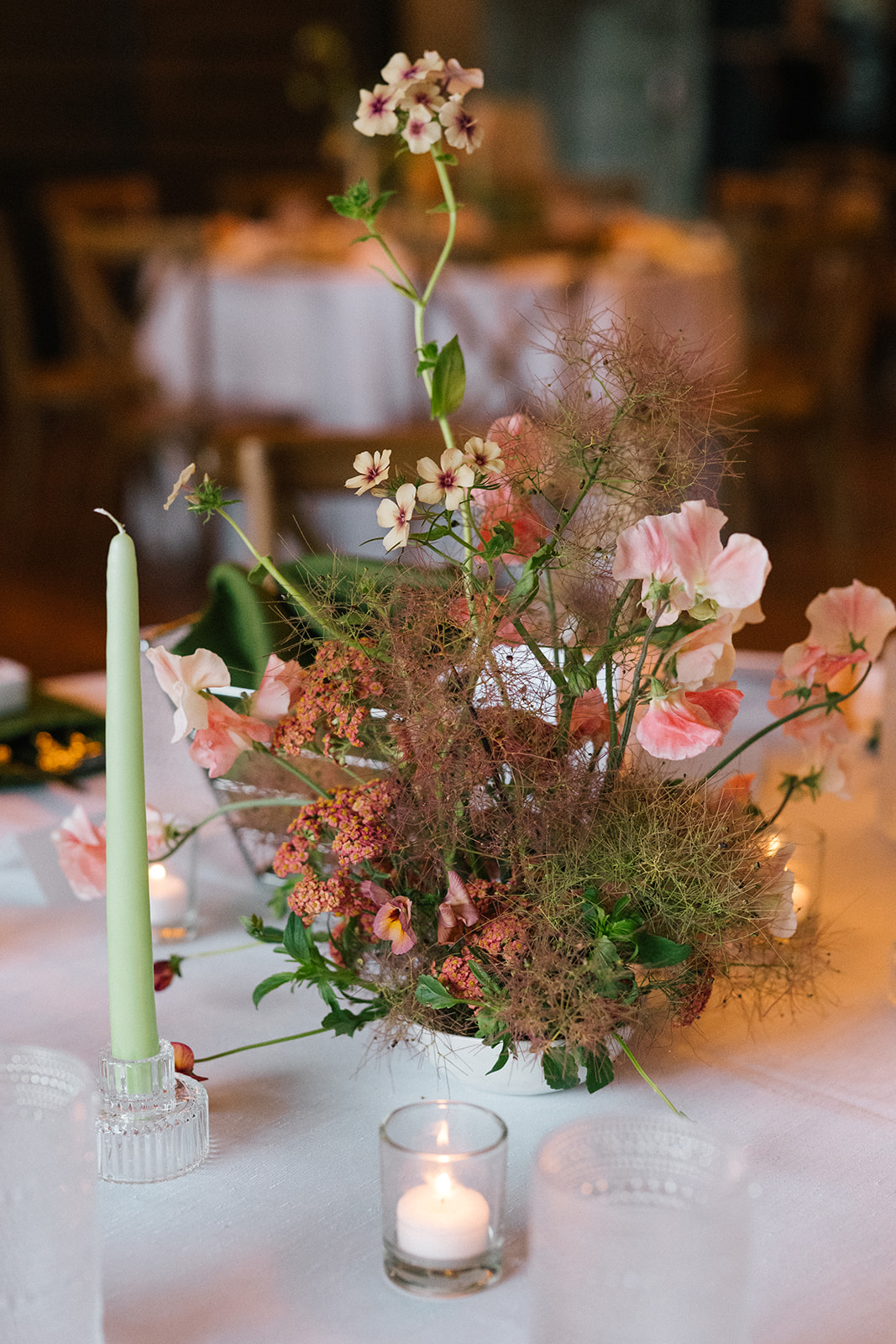 Garden-inspired floral centerpiece with soft pink blooms and candles on a reception table at the Fremont Foundry