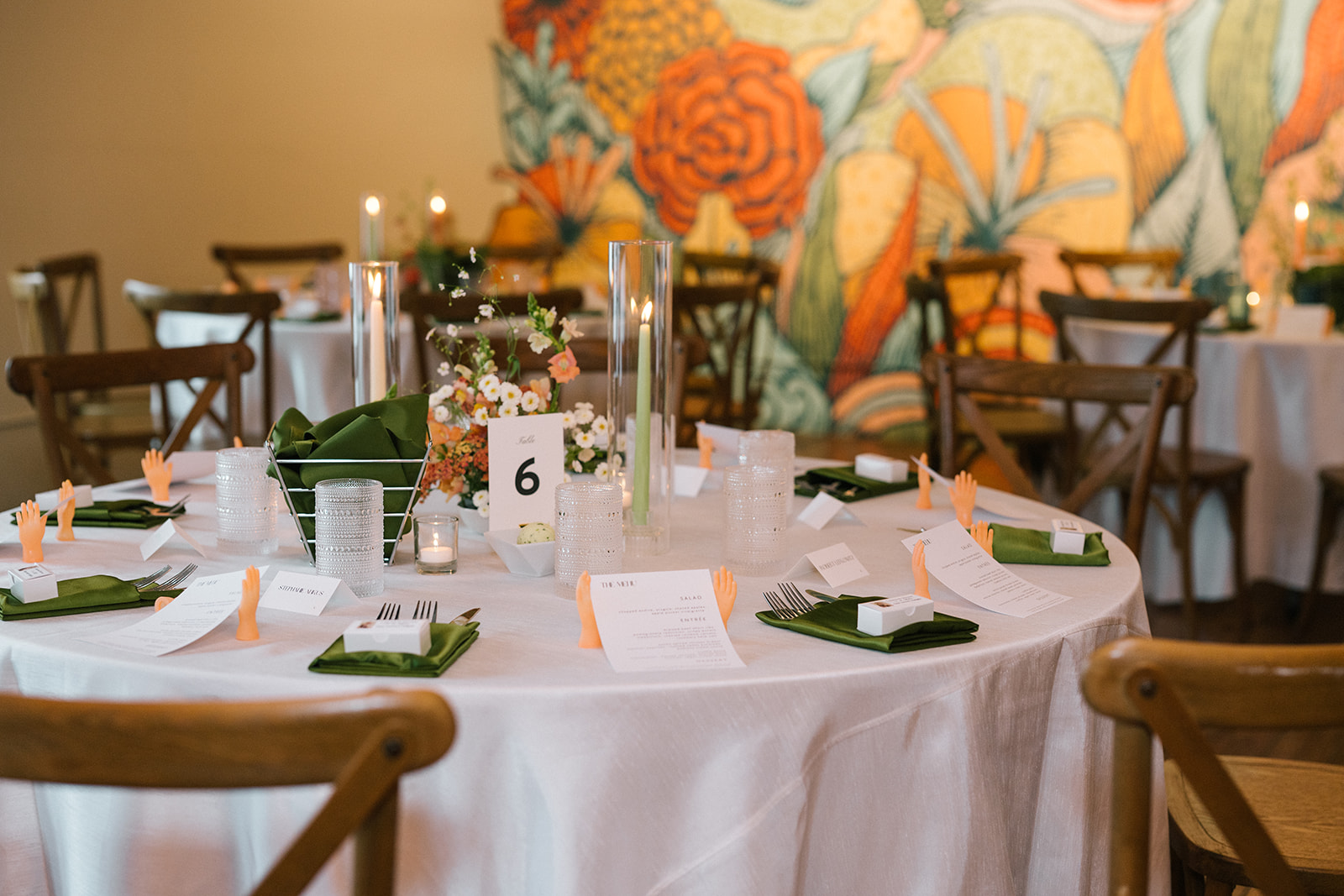 Reception table with green napkins, menus, candles, and small plastic hand place card holders at the Fremont Foundry