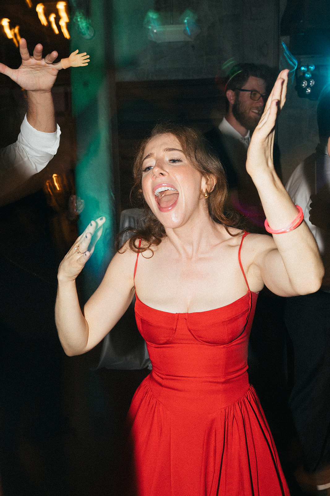 Wedding guest in a red dress dancing with her hands in the air at the Fremont Foundry reception