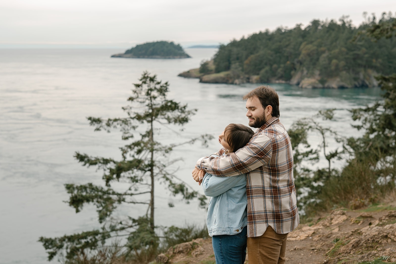 Jonathan holds Ashley close as they overlook the water at Deception Pass, sharing a quiet moment after their proposal.