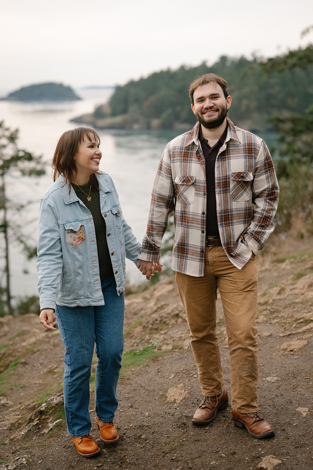 Jonathan and Ashley walk hand in hand along the cliffside trail at Deception Pass after getting engaged.
