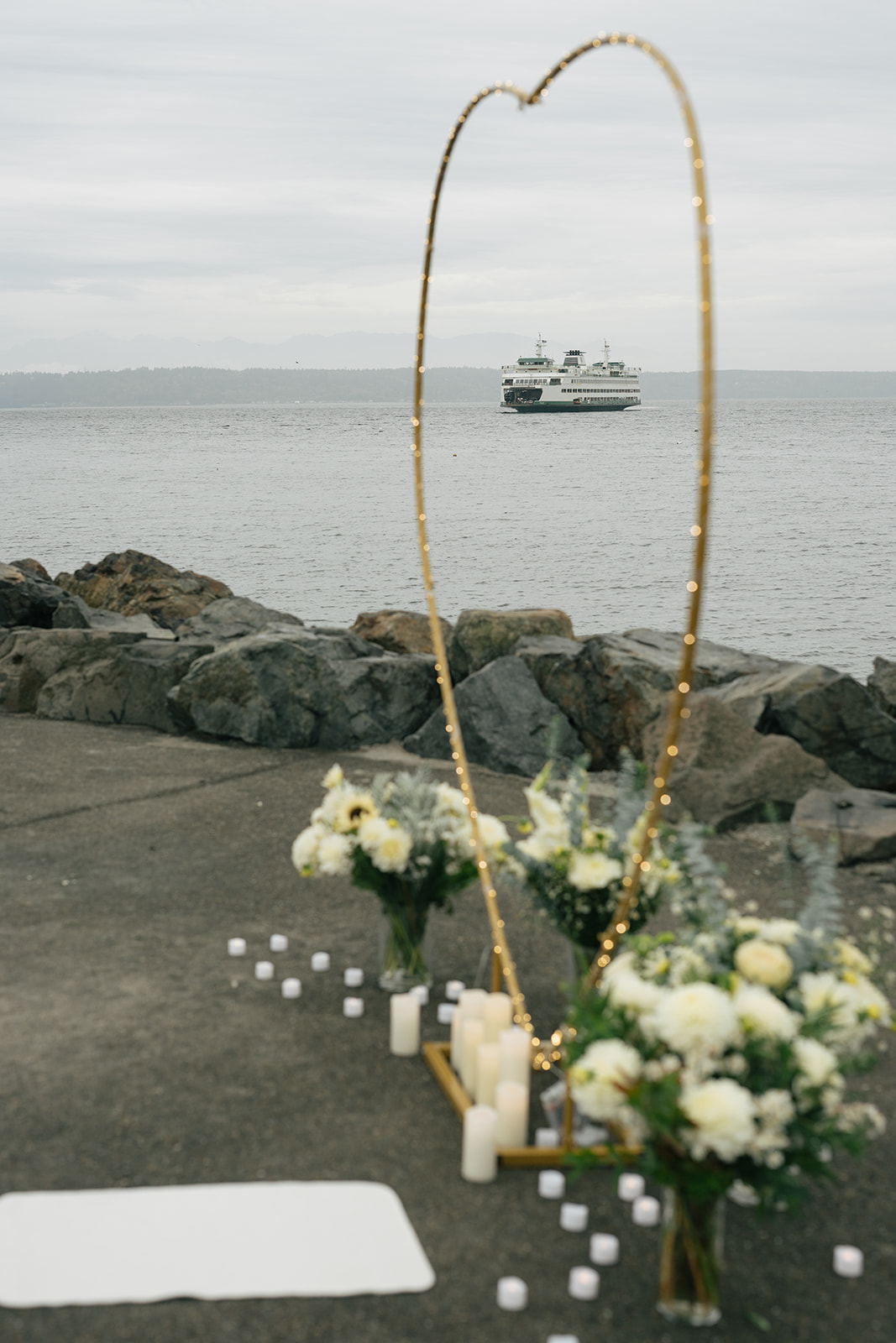 A heart-shaped arch framed against the water with a ferry passing in the background.