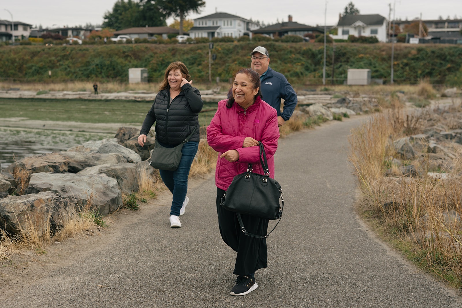 Smiling family members walk along the waterfront path to join Brad and Aysha after the proposal.