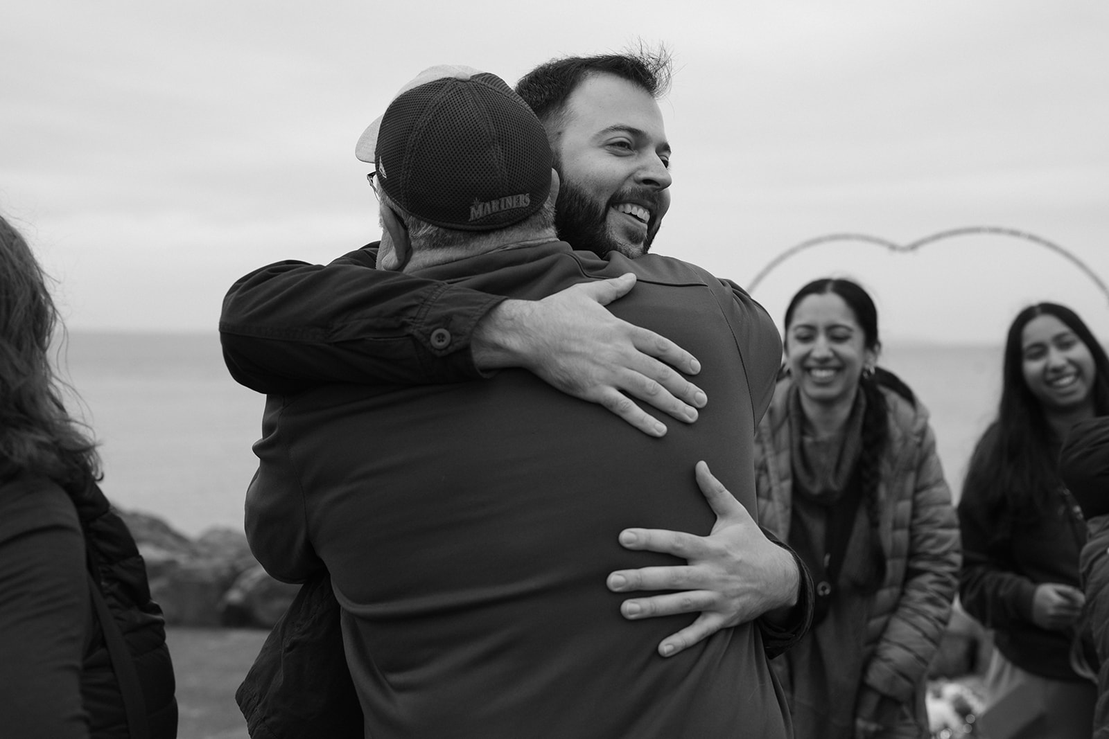 Brad hugs a family member tightly in an emotional black and white moment after the proposal.
