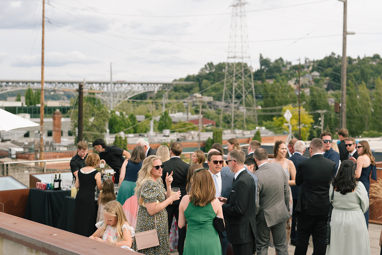 Wedding guests mingling during cocktail hour on the Fremont Foundry rooftop with views of the Fremont Bridge and Seattle skyline