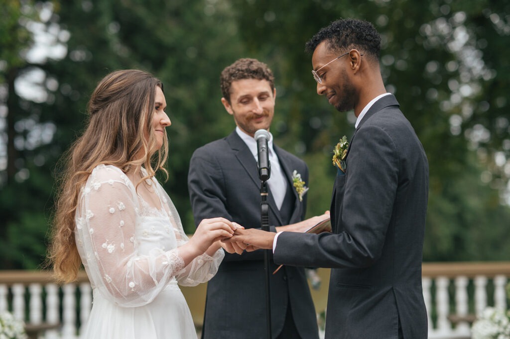 Bride placing ring on groom’s finger during wedding ceremony