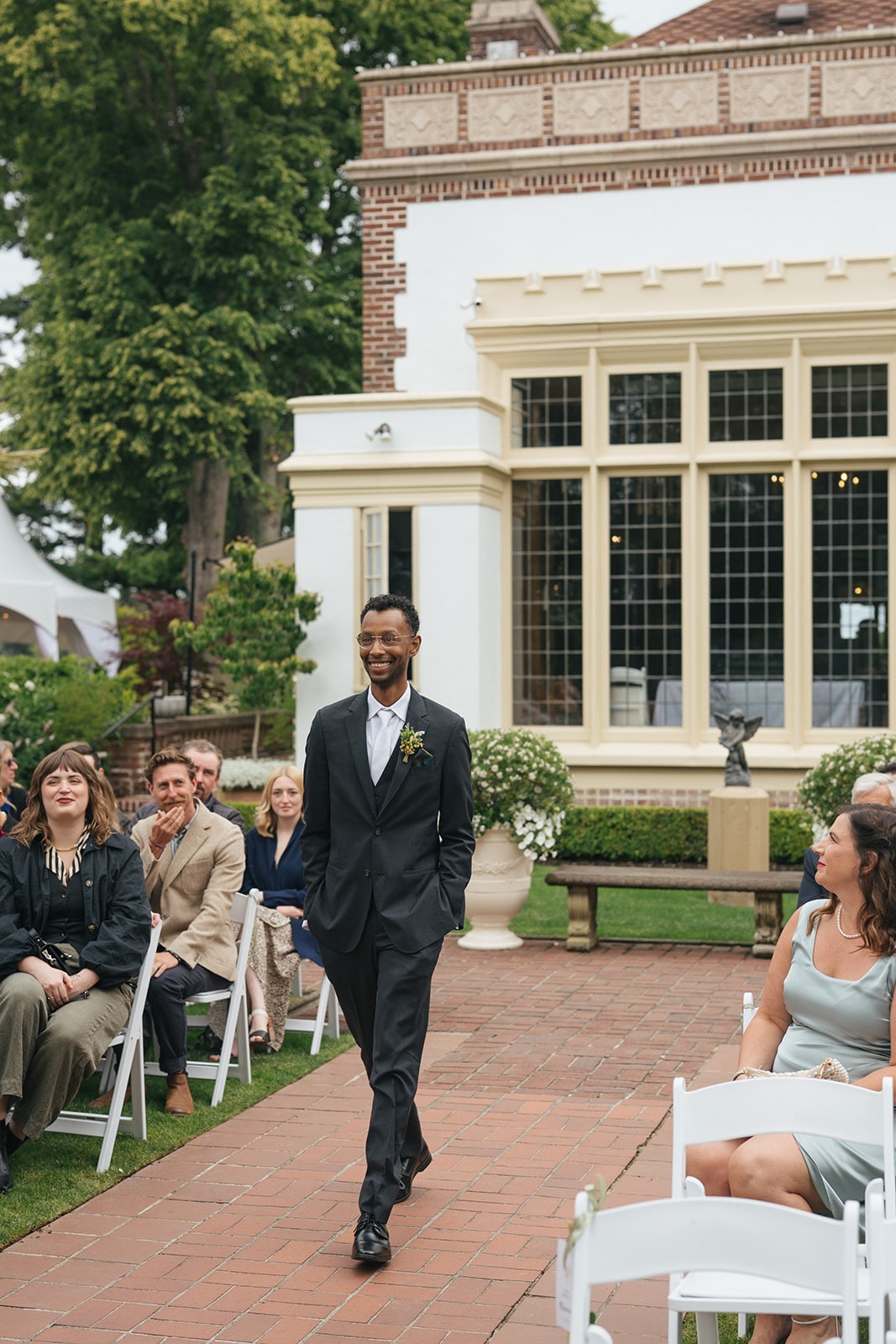 Groom walking past seated guests during outdoor wedding ceremony at Lairmont Manor