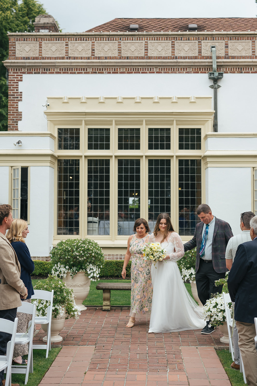 Bride walking down the aisle with her parents during outdoor ceremony at Lairmont Manor
